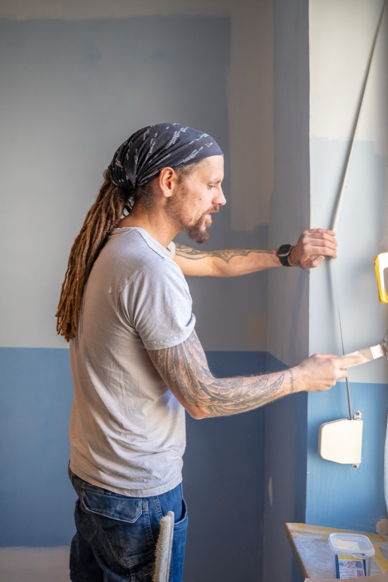 Maler streicht eine Wand in Blau