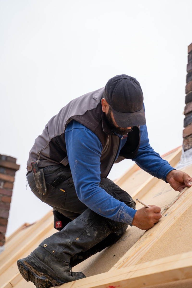 Dachdecker beim Vermessen auf dem Dach